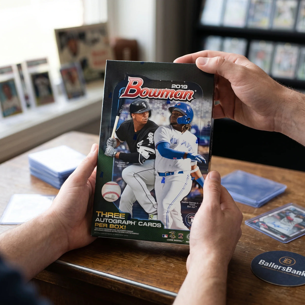 Collector hands displaying 2019 Topps Bowman Baseball Jumbo Hobby Trading Cards on a premium card-shop desk.