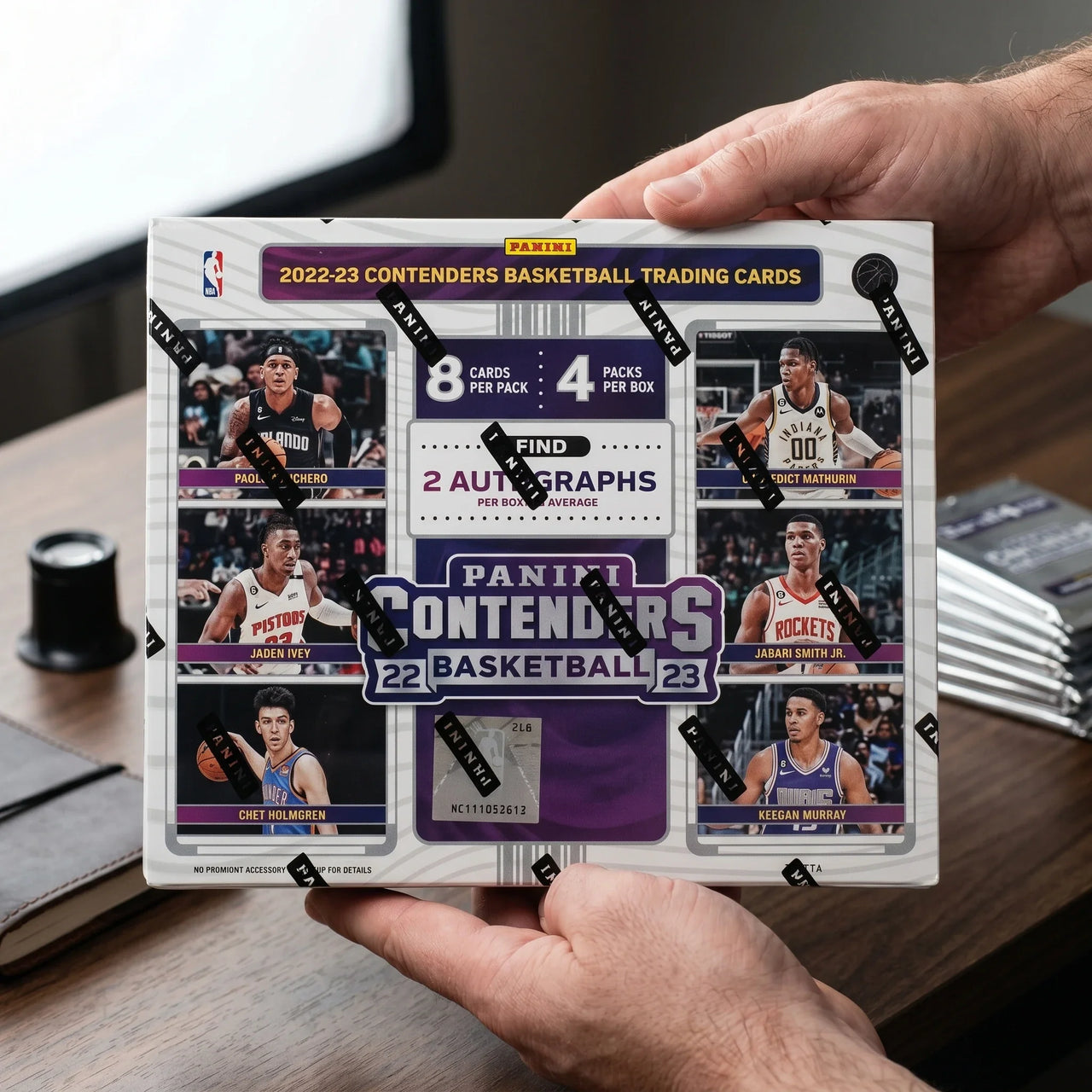 Collector hands displaying 2022-23 Panini Contenders Basketball Hobby Trading Cards on a premium card-shop desk.