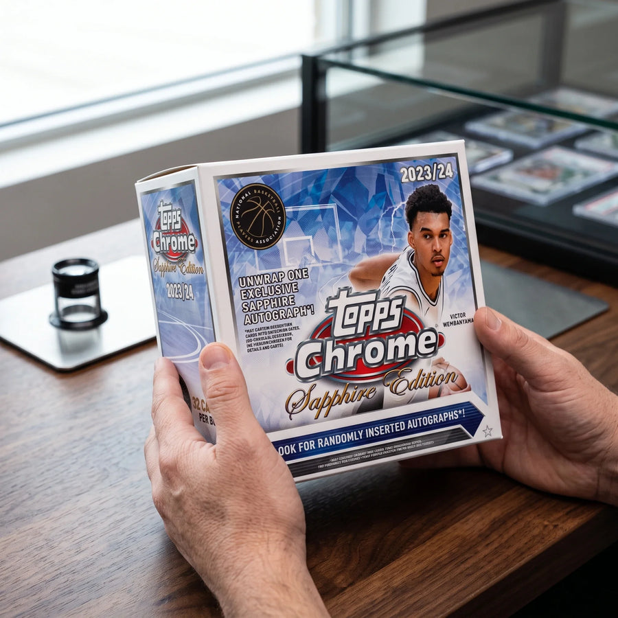 Collector hands displaying 2023-24 Topps Chrome Basketball Sapphire Edition Hobby Trading Cards on a premium card-shop desk.