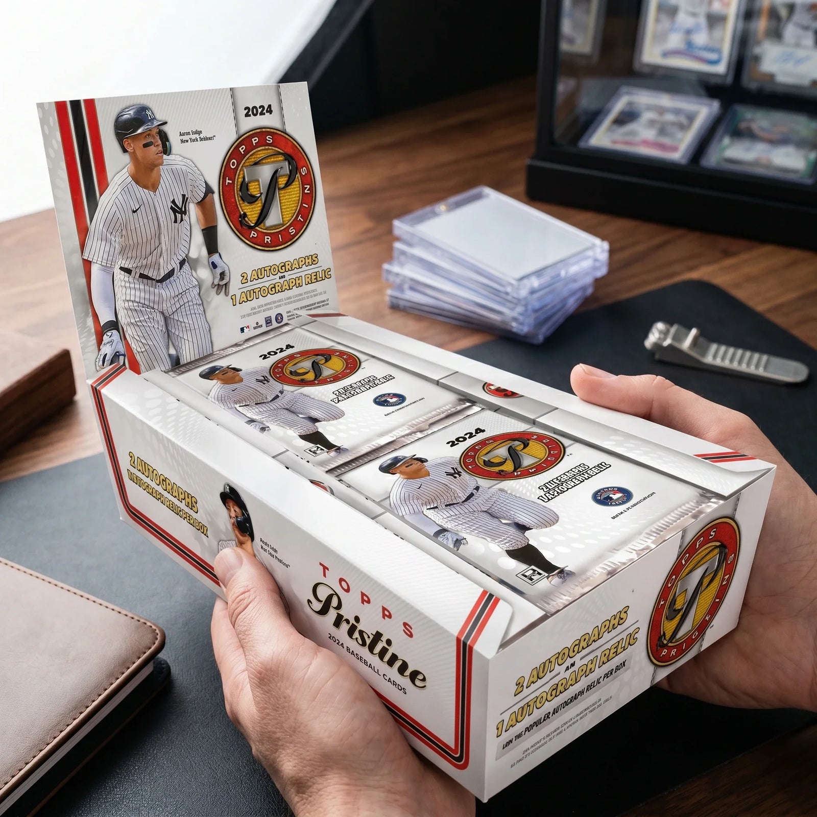 Collector hands displaying 2024 Topps Pristine Baseball Hobby Trading Cards on a premium card-shop desk.