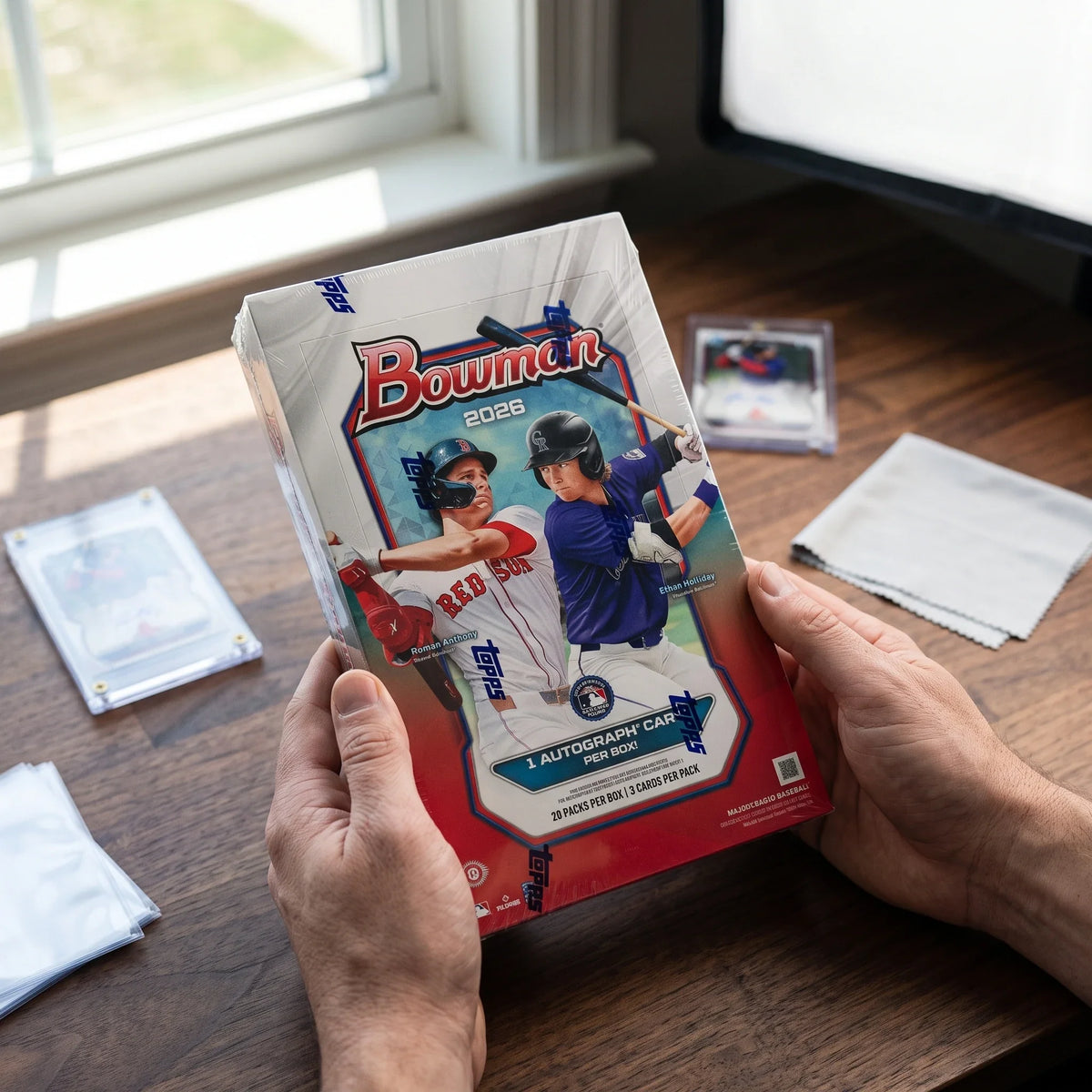 Collector hands displaying 2026 Topps Bowman Baseball Hobby Trading Cards LV on a premium card-shop desk.