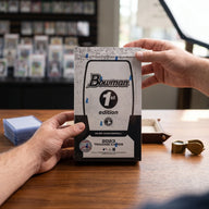 Collector hands displaying 2023 Bowman Baseball 1st Edition 12 Box Lot Prospect Cards (Ships Sealed Only) on a premium card-shop desk.