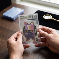 Collector hands displaying Pete Dunne WWE Autographed 2022 Panini Prizm #68 Beckett Fanatics Witnessed Authenticated 10 Card on a premium card-shop desk.