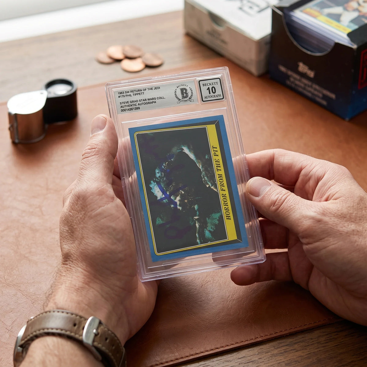 Collector hands displaying Phil Tippett Star Wars Autographed 1983 Topps Return of the Jedi #179 BAS Authenticated 10 Card on a premium card-shop desk.